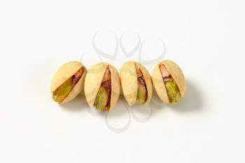 four pistachio nuts on white background