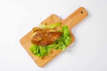 Chicken breast fillet with spicy rub on wooden cutting board