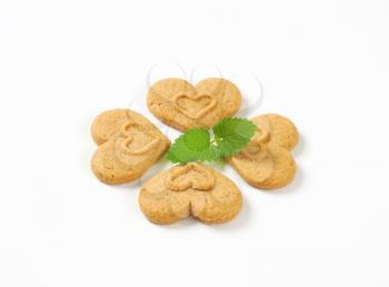 four heart-shaped cookies and mint on white background