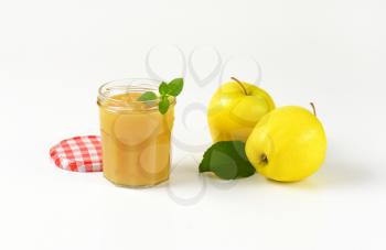 jar of applesauce and two yellow apples