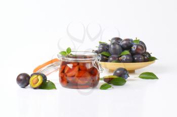 plum compote in a preserving jar and plate of fresh plums