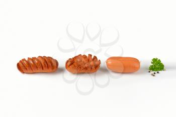 raw and roasted sausages on white background