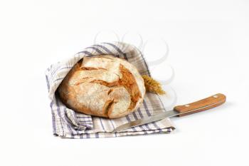loaf of bread in checked tea towel and kitchen knife