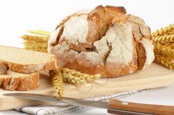 fresh bread - whole cob and slices - on wooden cutting board