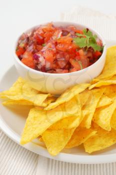 tortilla chips and bowl of salsa fresca on white plate