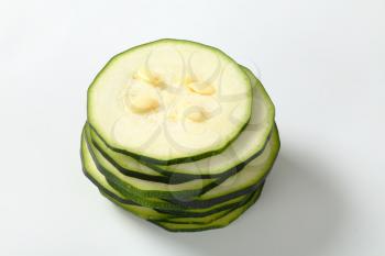 stack of thin slices of fresh zucchini on a white background