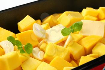 fresh pumpkin cubes with garlic and butter in a baking pan
