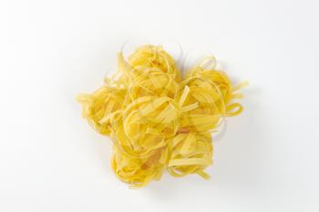 Dried ribbons of pasta coiled into nests