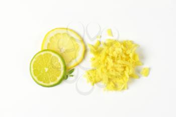 grated fresh ginger and slices of lime and lemon on white background