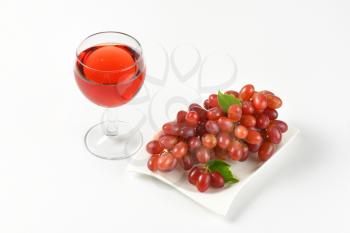 plate of ripe red grapes and glass of red wine