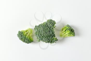 Fresh broccoli florets on off-white background