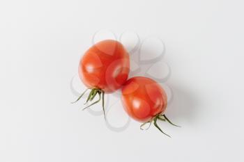 Two fresh red tomatoes on off-white background