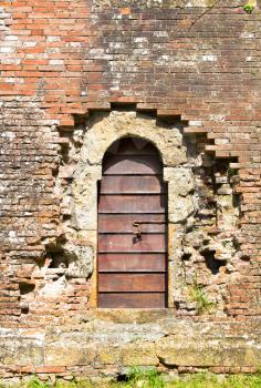 Arched entrance with old wooden door in aged brick wall