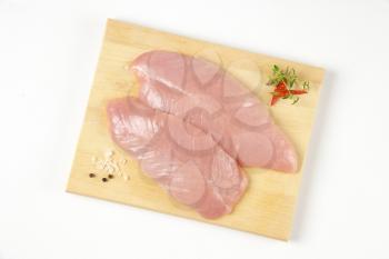 raw turkey breast fillets on wooden cutting board