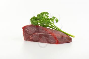 raw beef rump and fresh parsley on white background