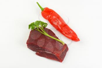 raw beef rump, fresh parsley and red pepper on white background