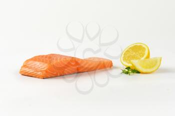 Fresh salmon fillet and lemon on white background