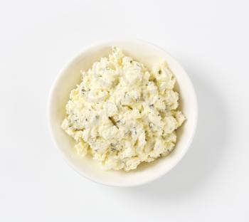bowl of homemade cheese spread with herbs on white background