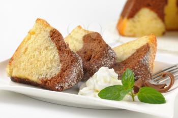 detail of marble bundt cake slices and whipped cream on white plate