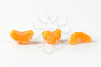 three separated segments of tangerine on white background
