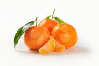 three whole tangerines with separated segments on white background