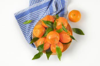 plate of ripe tangerines on checkered dishtowel