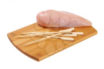 raw chicken breast and wooden skewers on wooden cutting board