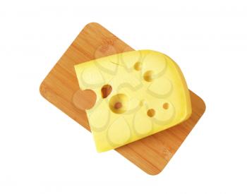 wedge of medium-hard Swiss cheese on cutting board