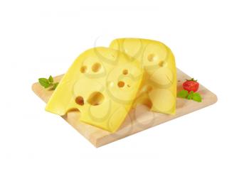 two wedges of Swiss cheese on wooden cutting board