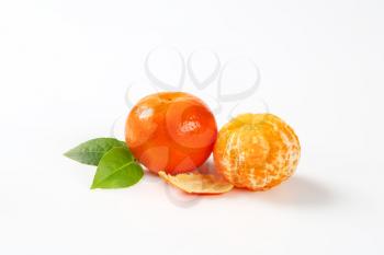 two fresh peeled and unpeeled clementines on white background