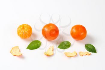 peeled and unpeeled clementines on white background