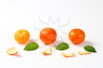 peeled and unpeeled clementines on white background