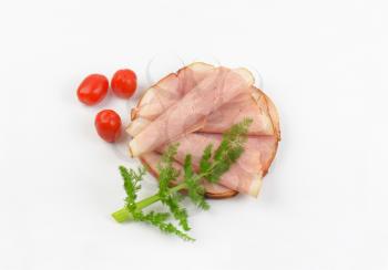 stack of ham slices with fresh dill and cherry tomatoes on white background