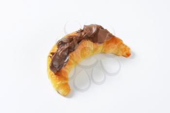 croissant topped with chocolate cream on white background
