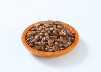 bowl of roasted coffee beans on white background