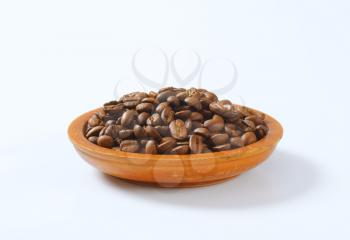 bowl of roasted coffee beans on white background