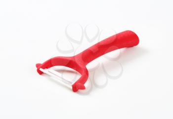 red vegetable and fruit peeler on white background