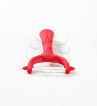 red vegetable and fruit peeler on white background