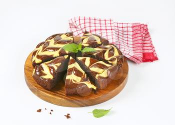 sliced chocolate cake with cream cheese on round wooden cutting board
