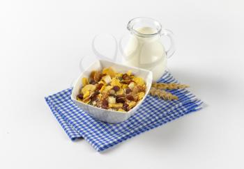 bowl of mixed breakfast cereals and jug of milk on blue checkered dishtowel