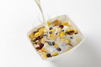 milk pouring into bowl of breakfast cereals
