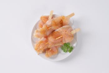 raw spiced chicken skewers on white plate