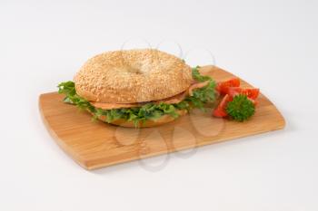 sesame bagel sandwich with smoked salmon on wooden cutting board