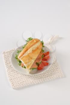 French bread sandwich with smoked salmon on white plate