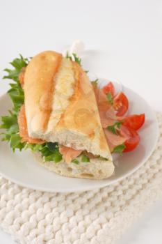 French bread sandwich with smoked salmon on white plate