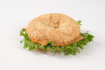 sesame bagel sandwich with smoked salmon on white background