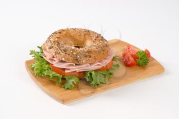 bagel sandwich with ham on wooden cutting board