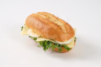 crusty roll sandwich with eggs and cheese on white background
