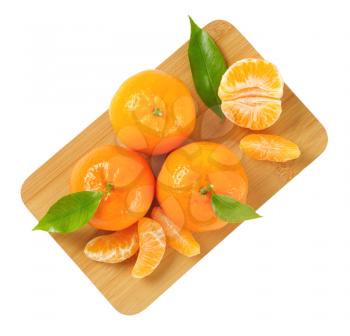 tangerines with separated segments on wooden cutting board