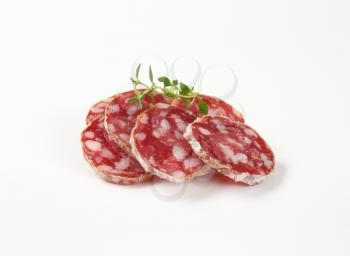 thin slices of dry cured sausage on white background